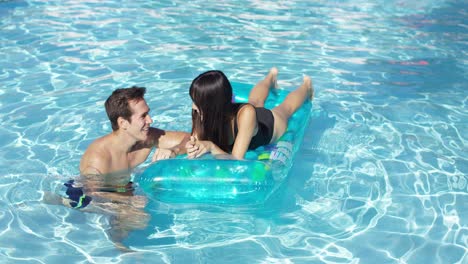 Feliz-Pareja-Joven-Flotando-Sobre-Un-Colchón-En-La-Piscina