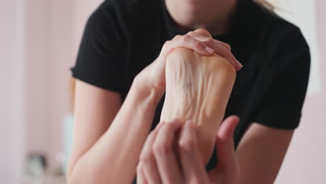 close view of massage therapist using finger to press center of client foot, focusing on reflex point and visible skin spot, calm therapeutic atmosphere with soft light in wellness treatment setting