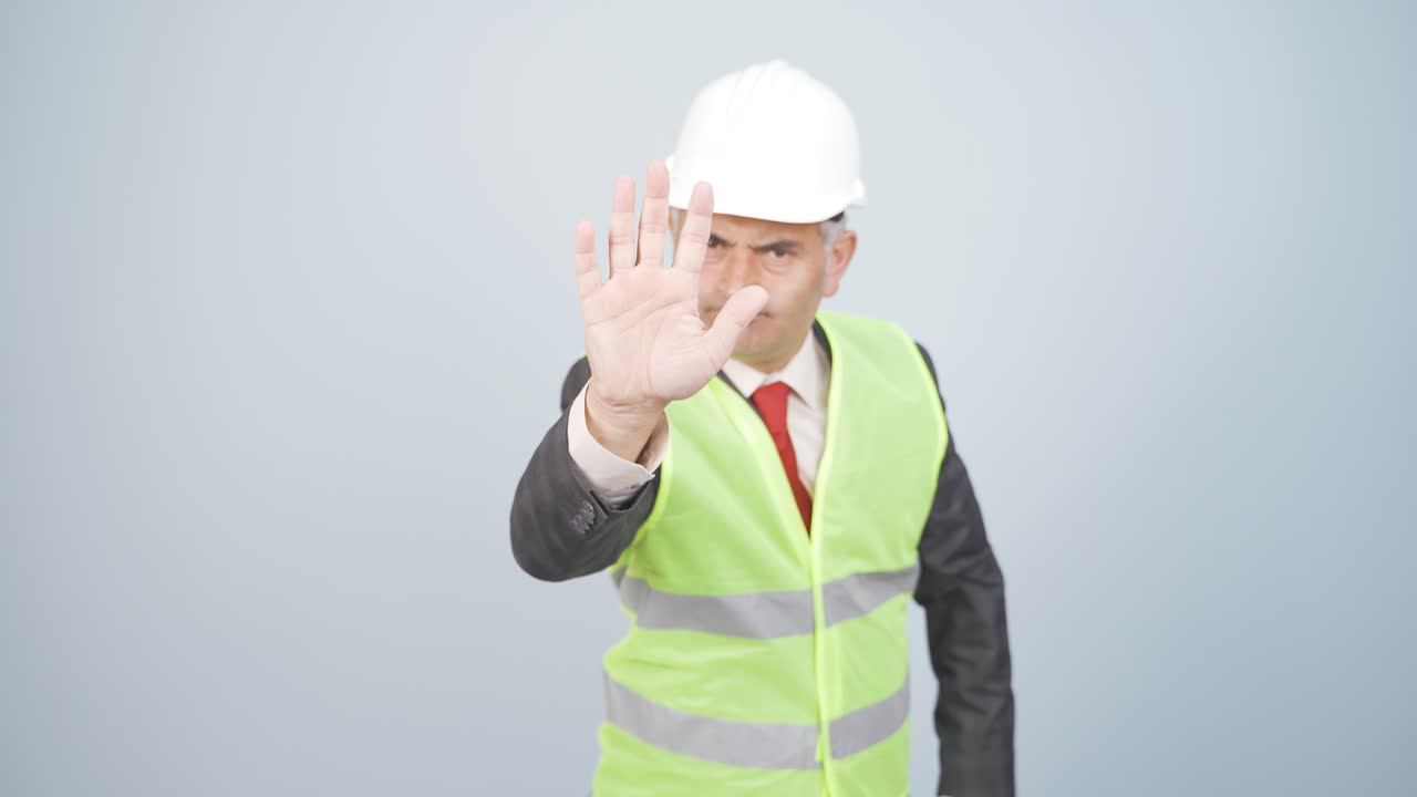 엔지니어는 카메라를 쳐다보고 정지 표지판을 만 ⁇ 니다.