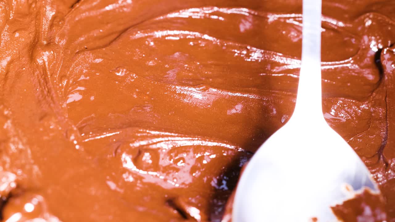 Spoon stirring smooth chocolate batter in bowl