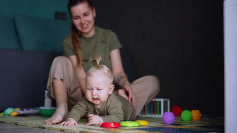 mom and her baby sit on the floor. baby boy is unhappy and wants to cry. parenting concept.