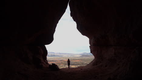 silhouette of woman with camera going out from cave 60fps