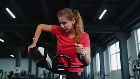 Entrenamiento-En-Grupo-De-Mujeres-Atléticas-Que-Se-Extiende-En-La-Rutina-De-Bicicleta-Estática-Giratoria-En-El-Gimnasio,-En-El-Interior