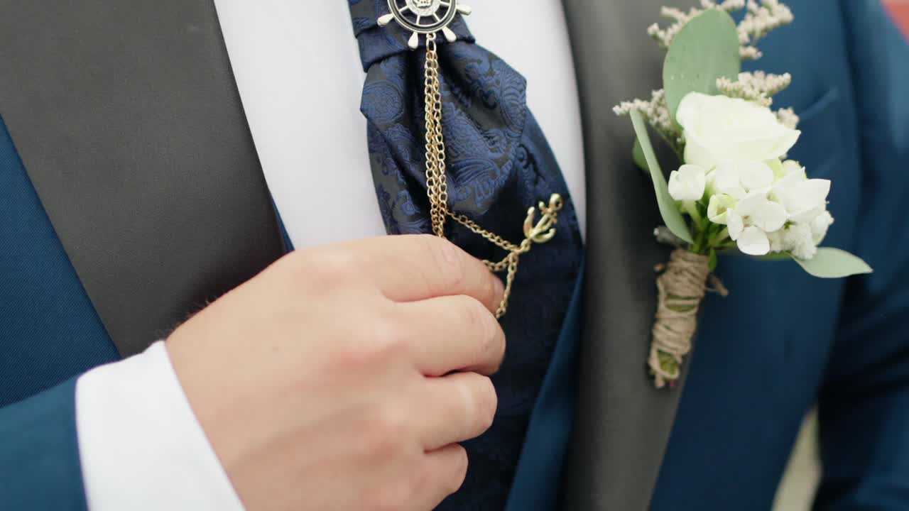 groom wearing a deep blue suit, gold chain, and white floral boutonniere