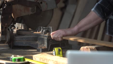 close up carpenter using circular saw cutting wooden plank in workshop . young man builder sawing board