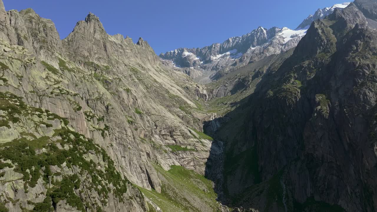 Aerial shot of steep granite cliffs and alpine peaks in the Bernese Alps, Switzerland, under a clear blue sky