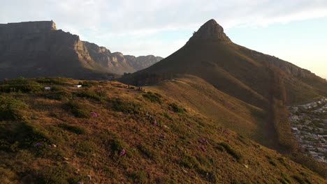 dramática toma aérea cinematográfica del pico de la cabeza de león con la montaña de la mesa y la colina de la señal durante la puesta de sol de la hora dorada