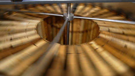 process of honey extraction in the electric centrifuge device. many wooden frames are rotated for taking honey out of cells.