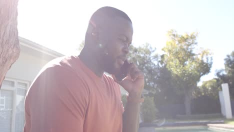 Happy-african-american-man-talking-on-smartphone-in-sunny-garden,-in-slow-motion