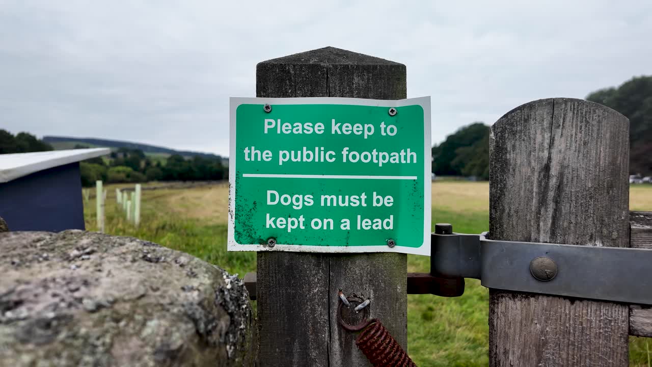 Green public footpath sign on wooden post reminding walkers to keep dogs on lead in County Durham countryside