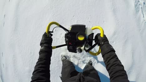 ice fisherman drilling in the snow