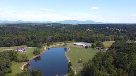 A-drone-shot-of-a-pond,-a-barn,-and-the-blue-ridge-mountains-in-the-distance