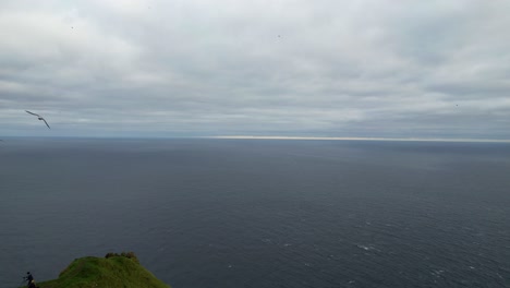 People-hiking-around-Kallur-lighthouse-while-seagulls-fly-in-Faroe-Islands