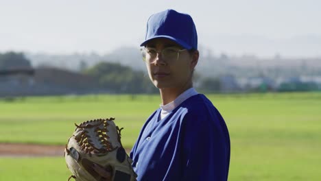 retrato de caucásico de jugadora de béisbol, lanzador, sosteniendo la pelota en guante en el campo