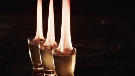 Video of lit alcohol in glasses with yellow fire flames and copy space on black background