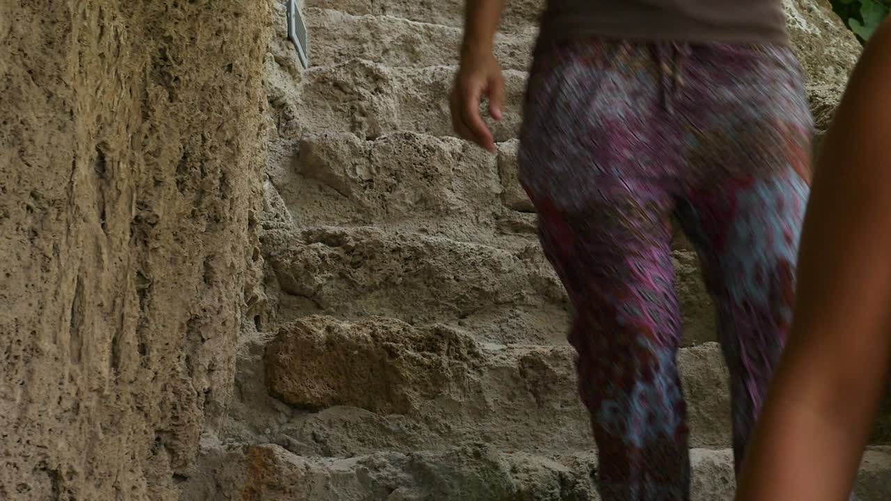 Toeristen dalen af via stenen trappen die rechtstreeks in de rots van de grotten van de Nasrid Garden zijn uitgehouwen