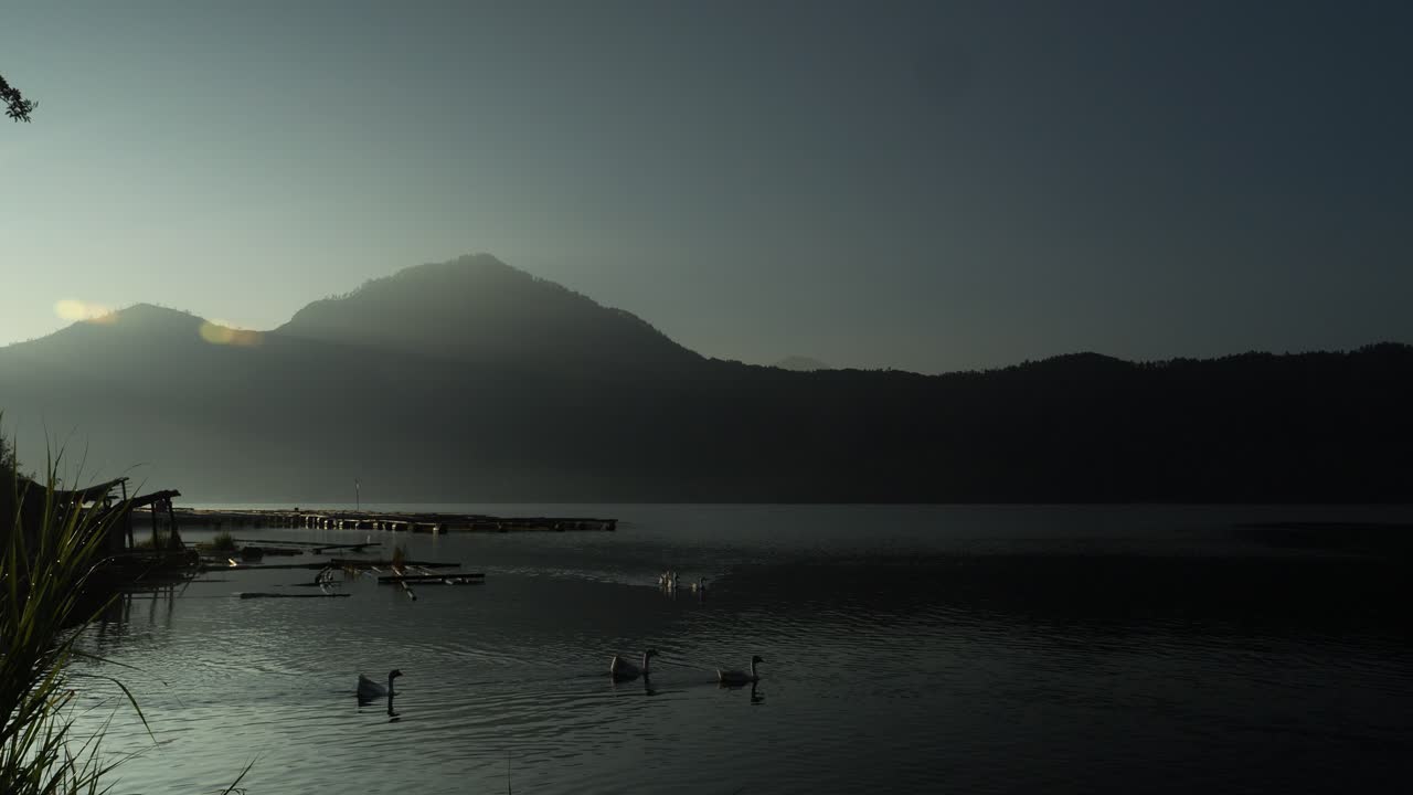 imagen ascendente del lago volcánico batur con vista a la montaña batur y el lago tranquilo con patos nadando en una hermosa mañana durante la hora dorada
