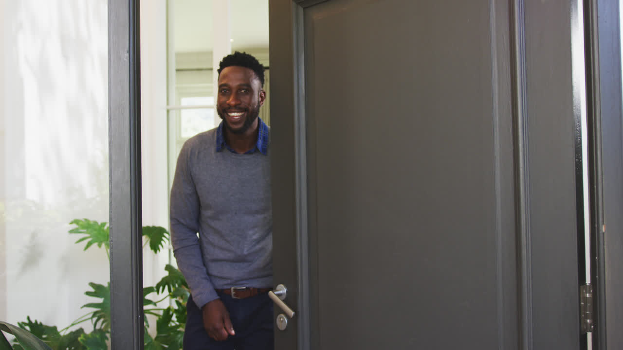 African American man opening a entrance door and looking at camera