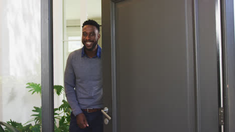 hombre afroamericano abriendo una puerta de entrada y mirando a la cámara
