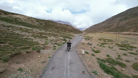 aerial tracking of biker on motorcycle riding a rural mountain road in spiti valley india