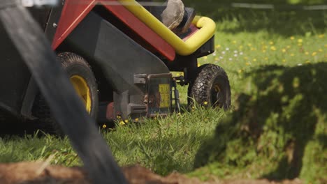 Person-in-high-rubber-boots-starts-mowing-lawn-with-a-tractor