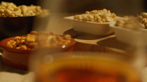 close up of hand choosing from bowls of cashews dry roasted peanuts and pistachio nuts in studio 2