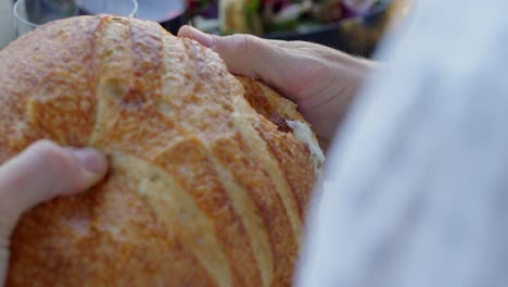 a person tears off a piece of bread at dinner