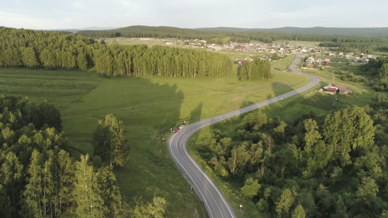 Ilmakuva mutkittelevasta tiestä maaseutumaiseman halki