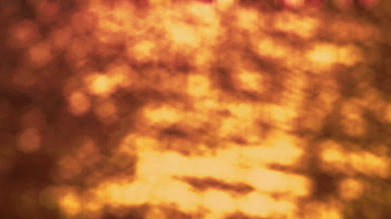 해가 지면 - 생생한 노란색, 오렌지색 및 암버색으로 파동하고 반이는 물 표면의 완전히 초점을 맞추지 않은 4k 의 아름다운 원활한 루프