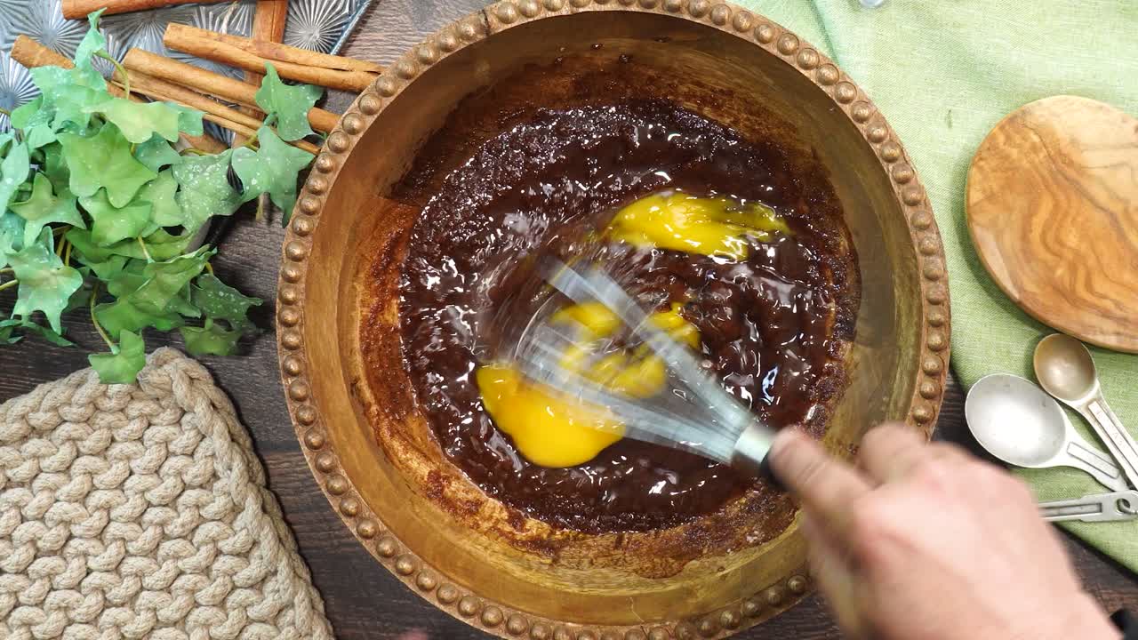 Baking a carrot cake loaf with cream cheese icing and topped with roasted salted pecans. Making a Autumn dessert with carrots, flour, sugar, nuts and frosting. Whisking eggs into the batter.