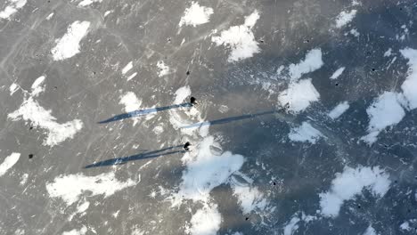 An-aerial-drone-shot-of-a-group-of-friends-playing-hockey-on-a-frozen-lake-on-a-winters-day