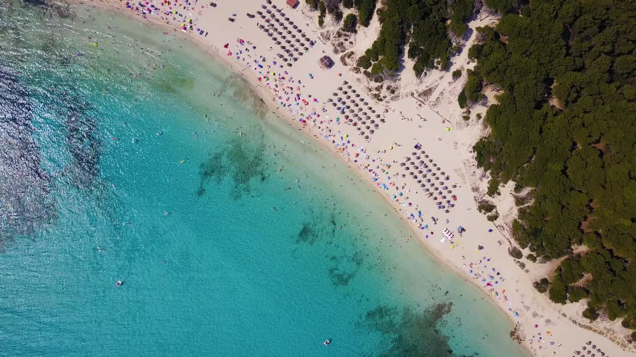 Drone orbiting while slowly descending down the beachfront of Cala Agulla, showing the crystal clear blue waters and sandy beaches in Llevant Peninsula in the island of Mallorca in Spain