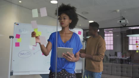 African-american-male-and-female-business-colleagues-brainstorming-in-meeting-room-using-glass-wall