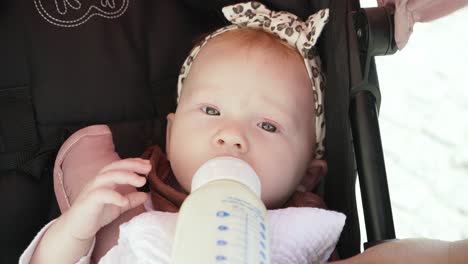 niña bebiendo su leche en un cochecito de bebé