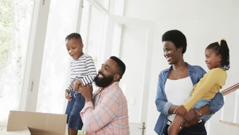 Feliz-Pareja-Afroamericana-Sosteniendo-A-Hijo-E-Hija-En-Casa,-Cámara-Lenta