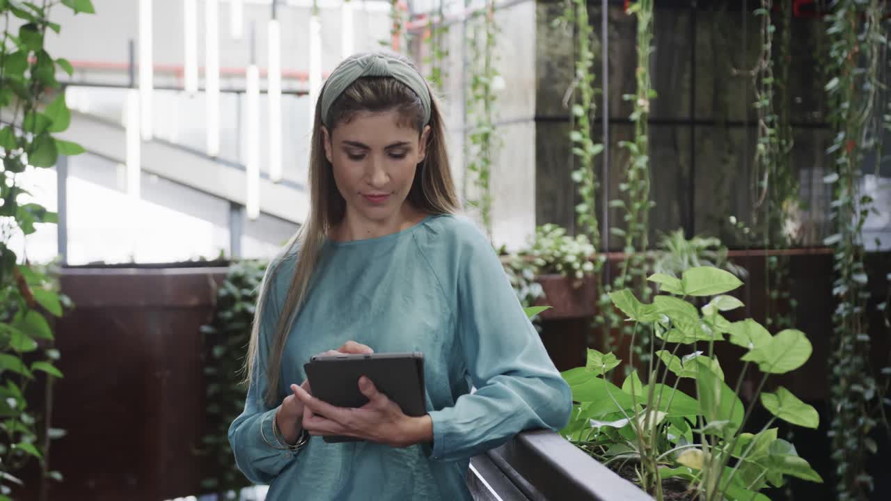 mujer caucásica feliz creativa usando una tableta en una oficina casual, en cámara lenta
