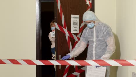 Medical-worker-opening-entrance-door,-sick-family-of-woman-with-daughter-at-home-during-coronavirus