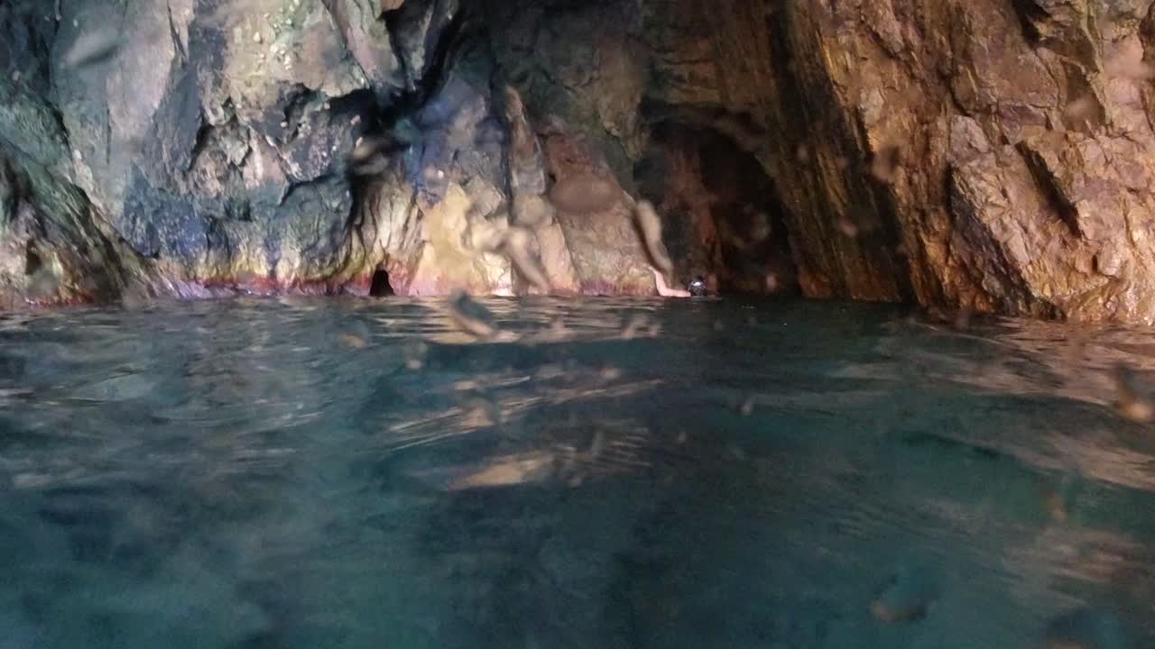 snorkeler는 영국령 버진 아일랜드에 있는 바다 동굴의 끝으로 돌아갑니다.