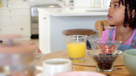 little girl enjoying breakfast with fruit and juice at home kitchen table