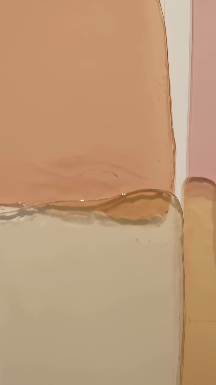 Vertical video: Lighting causing stacked translucent peach blocks showing ripple glints pink strip