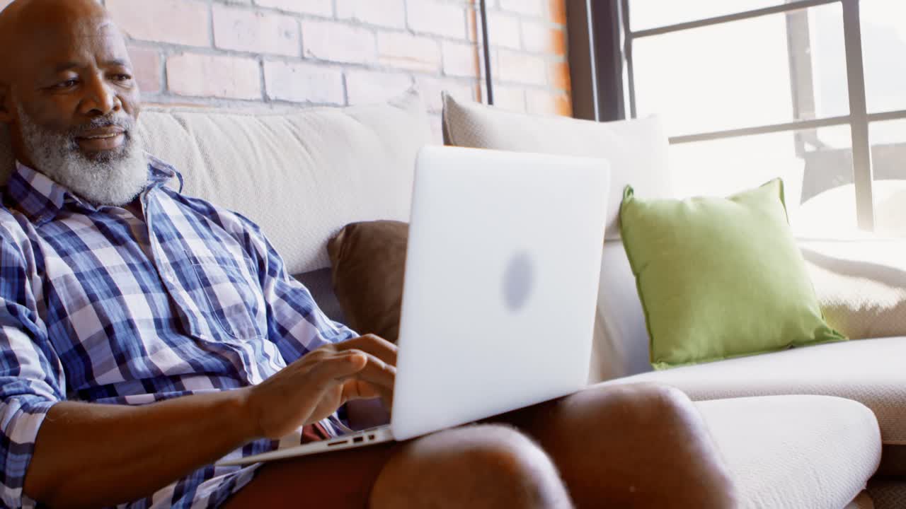Senior man using laptop in living room 4k