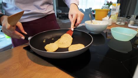 fotografía de una mujer cocinando panqueques en la cocina en casa por la mañana para el desayuno