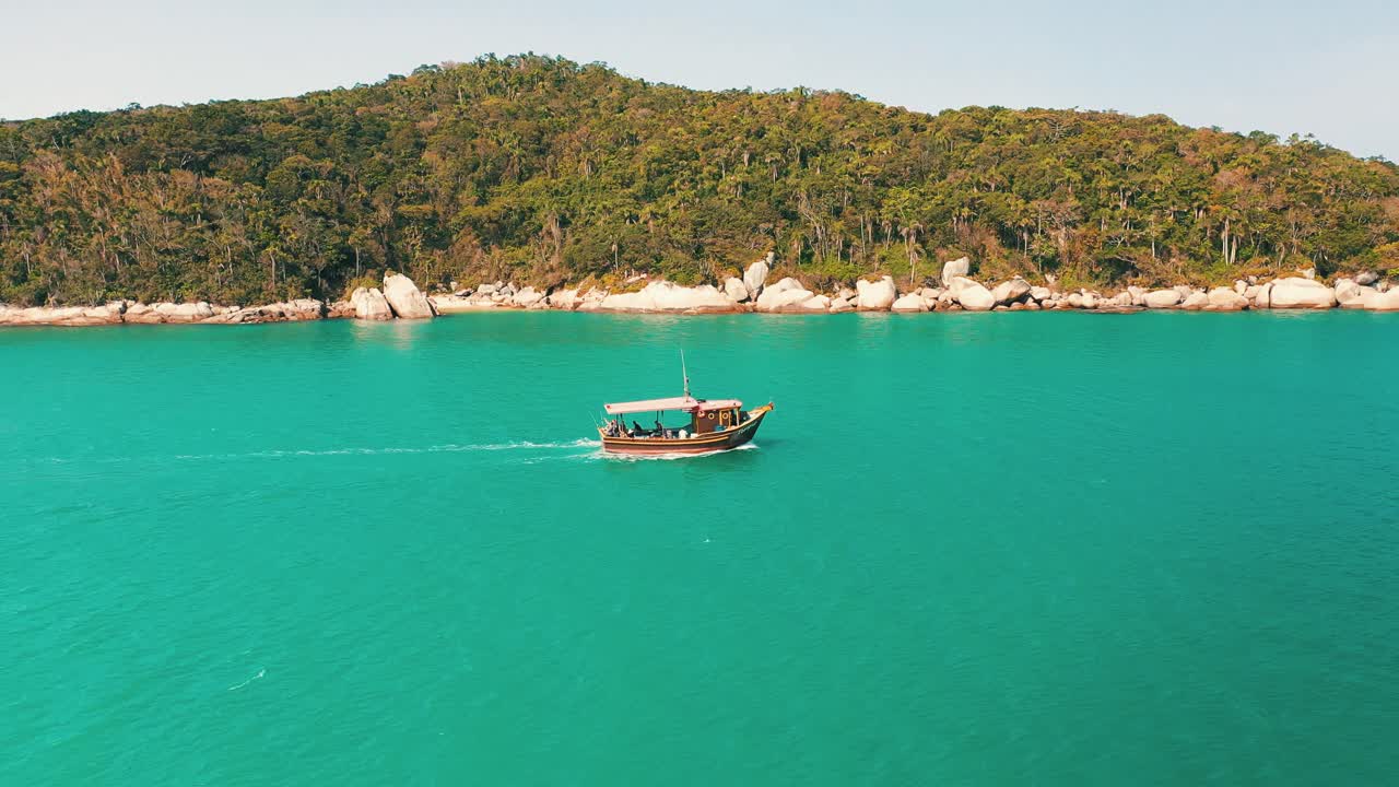갈매기 떼가 날아다니는 청록색 물색과 낙원 열대 우림 풍경을 지나가는 관광 보트의 측면 공중 전망