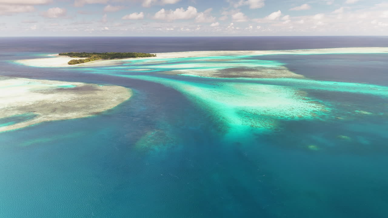 Cinematic aerial flyover revealing the glowing waters and sandy coastal shores near Palau. Wide cinematic drone shot