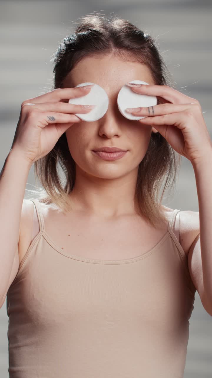 Vertical video: Beauty model acting silly with cotton pads over eyes