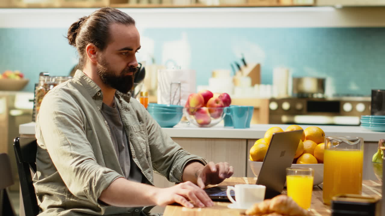 Man working from home in kitchen interior focused on online management