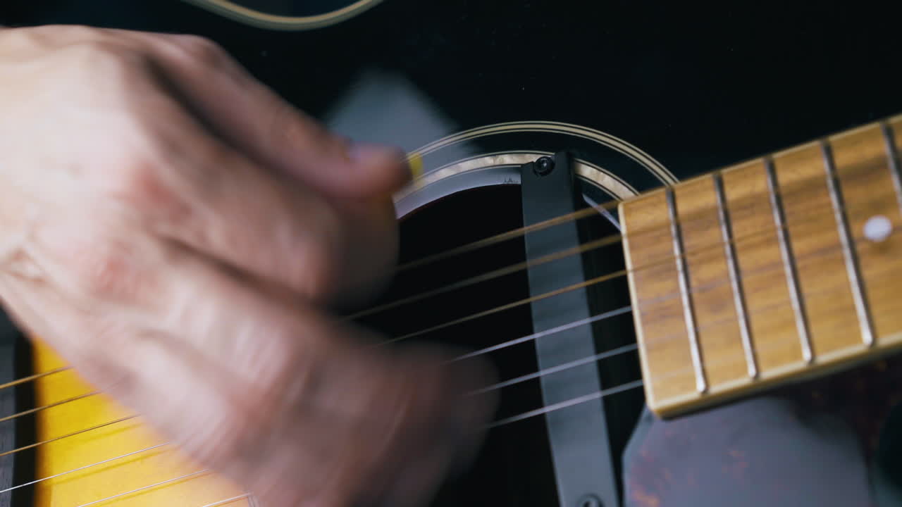 professional guitarist plays black and brown acoustic guitar