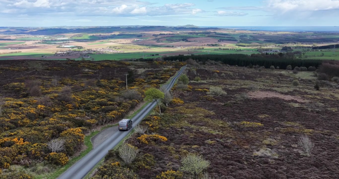 Vue aérienne d'un camping-car argenté roulant sur une route à voie unique dans les collines de Lomond, Fife, Écosse. La route relie la route principale de Falkland au parking de la randonnée de l'East Lomond.