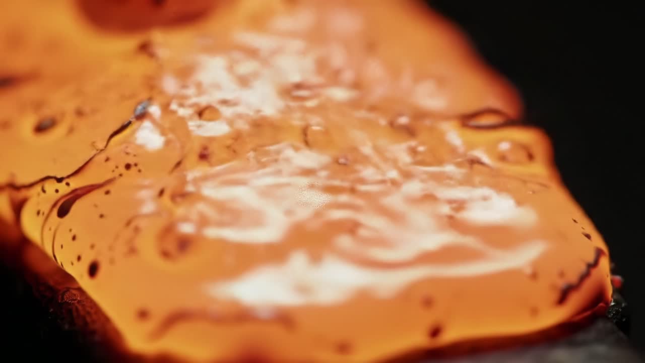 Farverig orange maling flyder jævnt på en overflade i en kunstnerisk demonstration