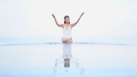 瘦弱的亞洲女人在無限泳池裡玩耍和噴水,慢動作